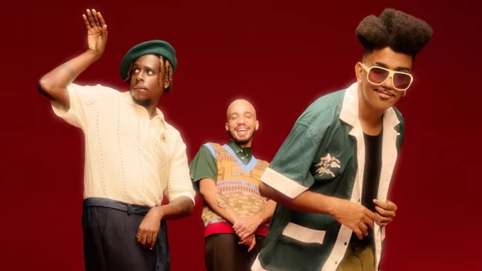 Os Garotin, grupo de músicos, ao vivo no Rio, durante a turnê Pro Brasil Cantar e Dançar, posando com alegria e energia em palco vermelho.