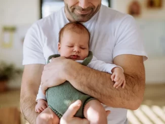 Pai segurando um bebê recém-nascido com expressão de carinho e proteção, simbolizando licença paternidade de até 20 dias após aprovação na Câmara.