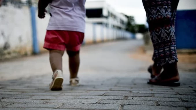 Imagem de duas crianças caminhando na rua, simbolizando as crianças órfãs de feminicídio que terão direito à pensão a partir de dezembro.