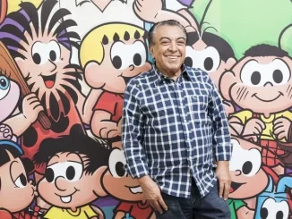 Homem sorridente ao lado de personagens clássicos de Maurício de Sousa, comemorando a declaração de São Paulo que reconhece suas obras como patrimônio cultural.