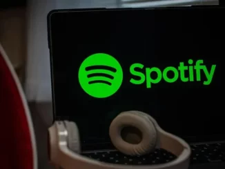 Imagem mostra logo do Spotify na tela de um laptop, com fone de ouvido na frente, indicando a polêmica sobre o processamento de streams falsos de Drake.