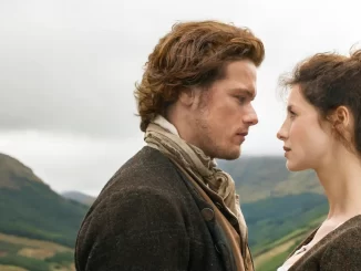 Cena da série Outlander, com um homem e uma mulher em um campo aberto, olhando um para o outro com uma expressão intensa, cenário de natureza ao fundo.