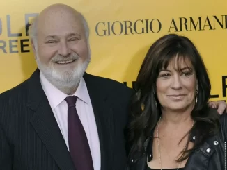 Imagem de ator Rob Reiner e sua esposa Michele Singer juntos, ambos sorrindo, durante um evento em Los Angeles, com fundo amarelo mostrando marcas de moda.