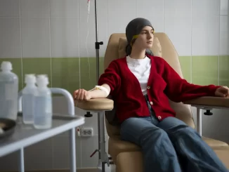 Paciente jovem recebendo tratamento de quimioterapia em hospital, símbolo do aumento de casos de câncer em jovens e a necessidade de diagnóstico precoce.