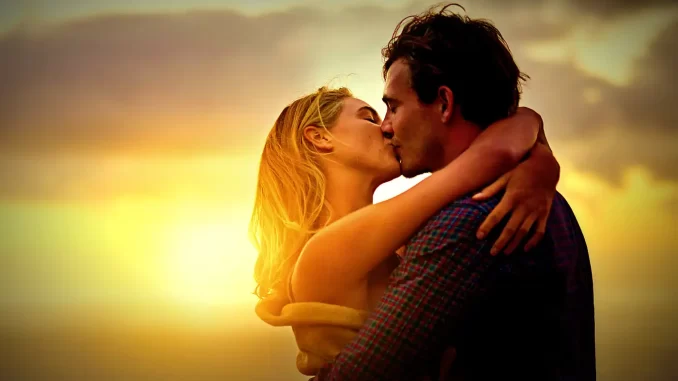 Casal trocando um beijo apaixonado ao pôr do sol, ilustrando como o beijo melhora humor, reduz estresse e fortalece vínculos de afeto entre as pessoas.