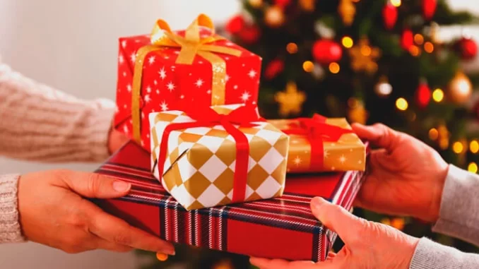 Brasileiros planejando aumentar gastos com presentes de Natal em 2025, representado por pessoas trocando presentes ao lado de uma árvore natalina decorada.