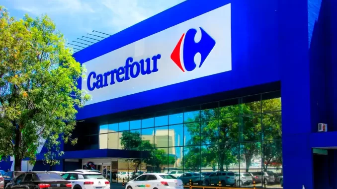 carrefour-troca-diretoria-no-brasil-frances-vice-ceo Fachada de uma loja Carrefour com sinal luminoso azul e carros estacionados na frente, símbolo de troca de diretoria no Brasil com introdução de francês como vice-CEO.