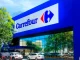 Fachada de uma loja Carrefour com sinal luminoso azul e carros estacionados na frente, símbolo de troca de diretoria no Brasil com introdução de francês como vice-CEO.
