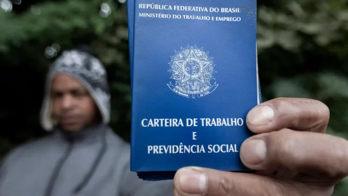 Homem segurando a carteira de trabalho e previdência social do Brasil, símbolo do mercado de trabalho para estrangeiros no país, com destaque para a presença de venezuelanos liderando esse grupo.