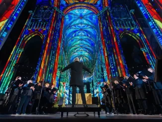 Espetáculo imersivo Luminiscence na Catedral da Sé em São Paulo, com projeções de luz colorida, música ao vivo e coro em celebração artística.