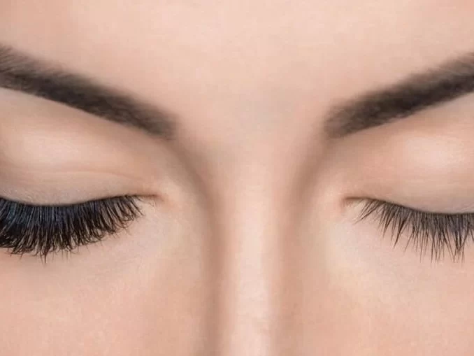 Imagem de olhos fechados com cílios longos e definidos, destacando cuidados para fortalecer cílios fracos e prevenir a queda dos fios.