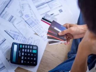 Pessoa analisando várias faturas e cartões de crédito para renegociar dívidas, com uma calculadora ao lado, na preparação para começar 2026 no azul.