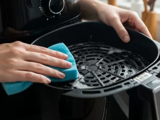 Pessoa limpando uma air fryer com uma esponja azul, demonstrando soluções naturais para a limpeza, remoção de gordura e odores.