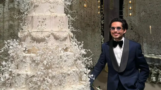 confeiteiro-dos-famosos-denilson-lima-divulga-audio-familia-rebate-video Confeiteiro dos Famosos Denilson Lima em evento com bolo decorado elaborado, usando terno preto com lapela de cetim, durante divulgação de áudio familiar em vídeo