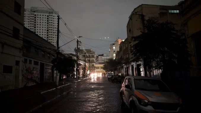 enel-promete-restabelecer-energia-grande-sao-paulo-ate-domingo Imagem retrata uma rua na Grande São Paulo à noite, com céu nublado e carros parados, evidenciando o impacto de uma falta de energia.