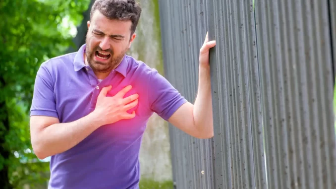 fatores-ambientais-elevam-risco-de-infarto-e-avc-alerta-medico Homem com dor no peito segurando o lado esquerdo do tórax ao ar livre, demonstrando risco de infarto causado por fatores ambientais, alertando sobre saúde cardiovascular.