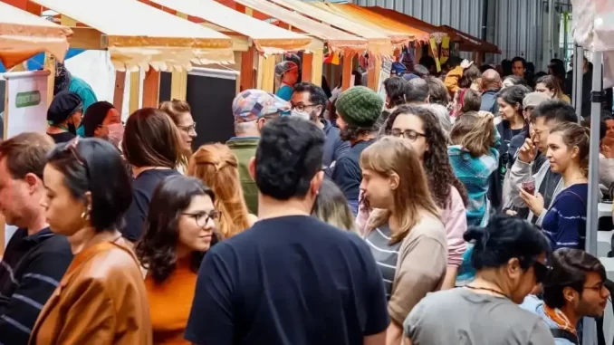 Pessoas na Feira Vegnice em São Paulo durante edição natalina com gastronomia vegana, artesanato e ambiente festivo.