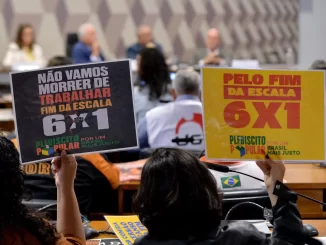 Manifestantes segurando cartazes de apoio ao fim da escala 6x1 e contra o trabalho na política, durante reunião no Congresso, defendendo o projeto de lei pela aprovação da proposta.