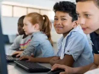 Crianças em sala de aula com computadores, ilustrando o compromisso do governo de garantir internet em todas as escolas públicas até 2026.