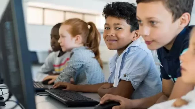 garantia-internet-escolas-publicas-2026 Crianças em sala de aula com computadores, ilustrando o compromisso do governo de garantir internet em todas as escolas públicas até 2026.
