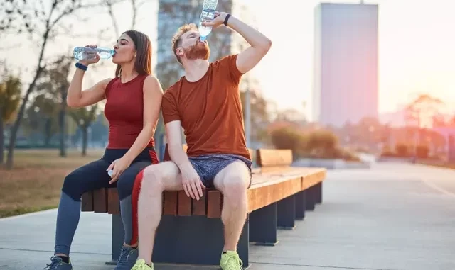 habitoseficientesparaaevoluicao-metabolicaparaemagrecer Homens e mulheres praticando hábitos diários que aceleram o metabolismo e favorecem o emagrecimento ao se hidratar com água durante atividade ao ar livre em parque urbano.