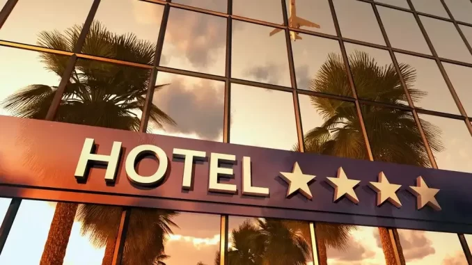 hoteisadotamhorariosoficiais24h Hotel com atendimento 24h, classificação de quatro estrelas, fachada de vidro refletindo palmeiras e céu ao pôr do sol, promovendo conveniência de check-in e check-out 24h.