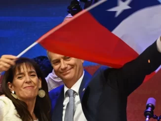 José Antonio Kast da extrema-direita é eleito presidente do Chile, celebrando com apoiadores e segurando a bandeira chilena em um evento político.
