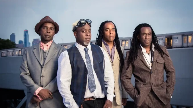 livingcolor-confirma-turne-brasileira-40-anos-2026-jpg Living Colour confirma turnê brasileira de 40 anos para 2026 com banda de rock liderada por membros com dreadlocks e estilo vintage, no cenário urbano ao pôr do sol.