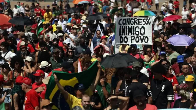 protestos-capitais-brasil-contra-pl-dosimetria Manifestação de protesto em capitais do Brasil contra o PL da Dosimetria, com grande concentração de pessoas, muitos com bandeiras e cartazes, incluindo um com a frase "Congresso inimigo do povo".