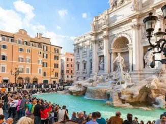 Turistas e visitantes na Fontana di Trevi, em Roma, com a fonte histórica e arquitetura ao fundo, próxima a uma mudança com cobrança de taxa a partir de fevereiro.