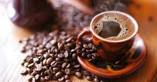 seis-bebidas-que-nao-devem-ser-tomadas-com-estomago-vazio Imagem de uma xícara de café preto ao lado de grãos de café, destacando as seis bebidas que não devem ser tomadas com estômago vazio para evitar desconforto ou problemas de saúde.