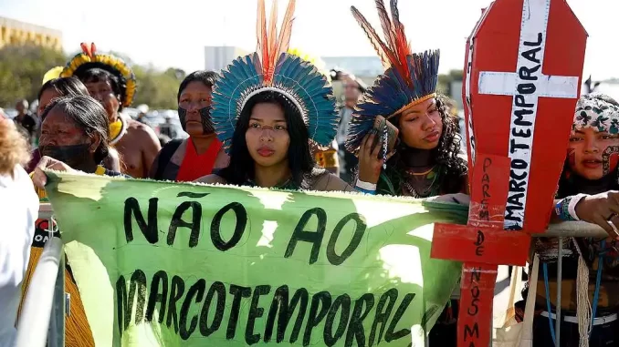 Protesto indígena com cartaz 'Não ao Marco Temporal' e defesa dos direitos ancestrais durante votação do STF sobre o marco temporal da terra indígena