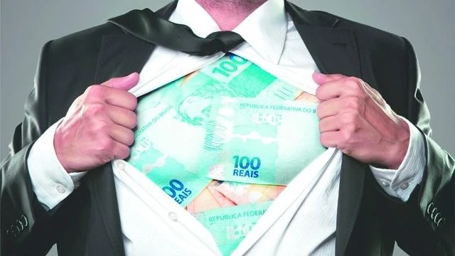supersalarios-inativos-ganham-acima-do-teto-4-bilhoes Imagem de um homem vestindo terno preto, abrindo a camisa para mostrar notas de dinheiro de R$ 100, simbolizando altos salários de inativos que ultrapassam o teto salarial, relacionados aos supersalários que totalizam quase R$ 4 bilhões.