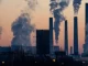 Vista de uma usine de energia com várias chaminés emitindo fumaça e poluição, simbolizando os desafios ambientais relacionados ao Acordo de Paris e as metas climáticas.