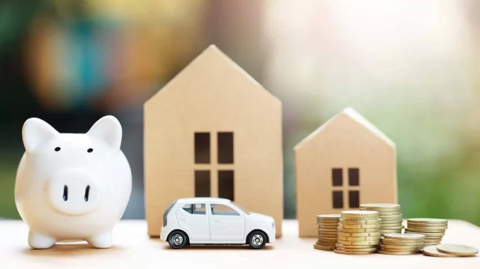 Imagem de uma parafernália de itens relacionados a pagamento de impostos como IPTU e IPVA, incluindo uma piggy bank, uma miniatura de carro, casas em miniatura e moedas, ilustrando opções de desconto ou parcelamento para quitar impostos municipais.