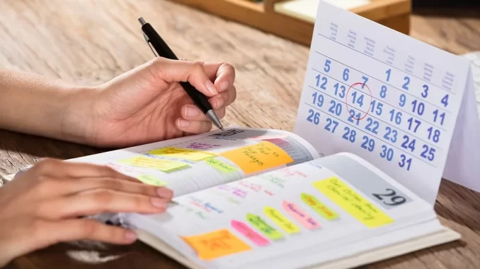 Jovem usando planner de papel para organizar suas tarefas, ilustrando o crescimento do uso de planners tradicionais entre os jovens devido à fadiga digital.