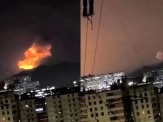 Incêndio e fumaça vulcânica vista ao fundo de uma cidade venezuelana, durante um possível ataque dos EUA, levando o governo venezuelano a declarar estado de emergência.