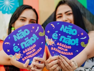 Duas mulheres segurando cartazes com mensagem contra o assédio no Carnaval 2026, na campanha "Não é Não" para conscientização.
