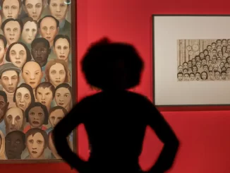 Pessoa observando obras modernistas de Tarsila do Amaral em uma exposição em Brasília, conectando arte modernista a debates contemporâneos, com destaque para retratos diversos e cores vibrantes.