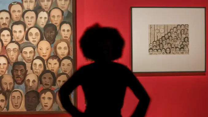 Pessoa observando obras modernistas de Tarsila do Amaral em uma exposição em Brasília, conectando arte modernista a debates contemporâneos, com destaque para retratos diversos e cores vibrantes.