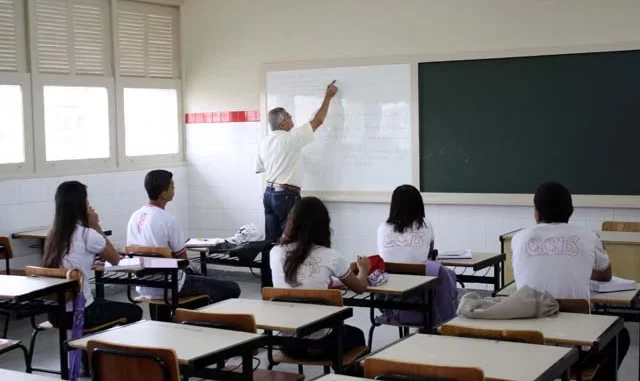 Sala de aula com estudantes do ensino médio e professor em quadro branco, ilustrando a crise de matrículas no Brasil na última década