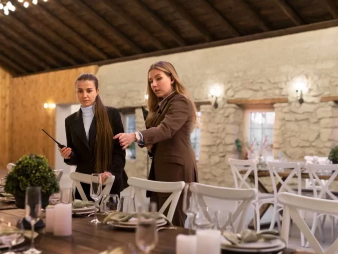 Duas mulheres organizam evento empresarial em sala de restaurante rústico, refletindo o crescimento do emprego e consumo no setor de eventos em 2026.