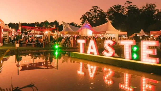 Taste São Paulo Festival celebra 10 anos no Parque Villa-Lobos com decoração iluminada, barraquinhas de comida, público aproveitando o evento ao entardecer.